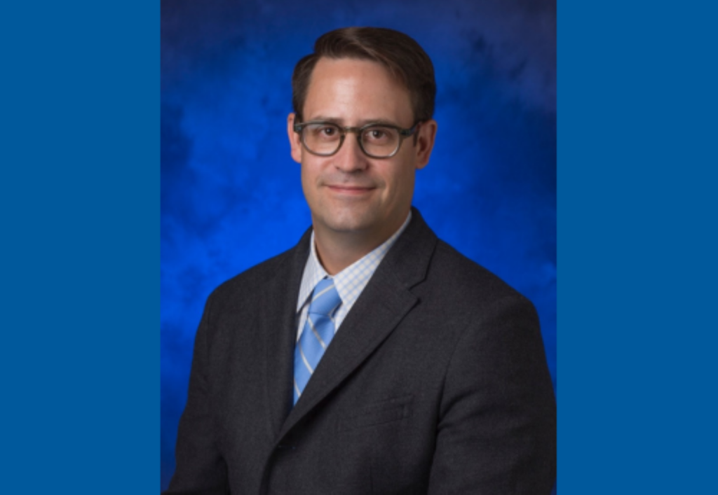Headshot of Chief Medical Officer James Butler with a blue background